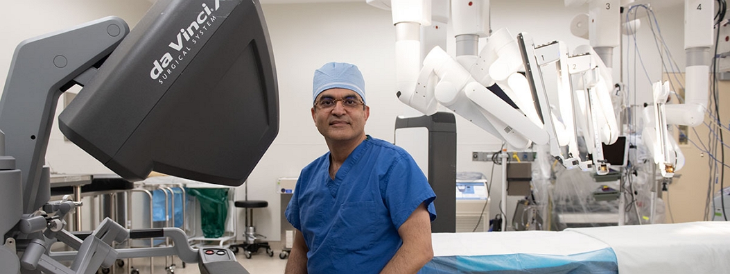 Dr. Masroor infront of robotic surgical equipment